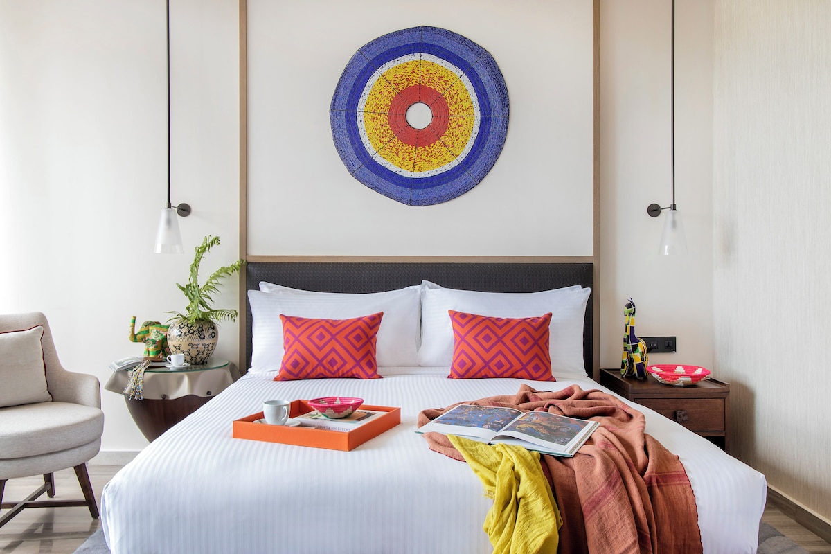 A neatly made bed with a tray of breakfast items, a book, and a blanket.