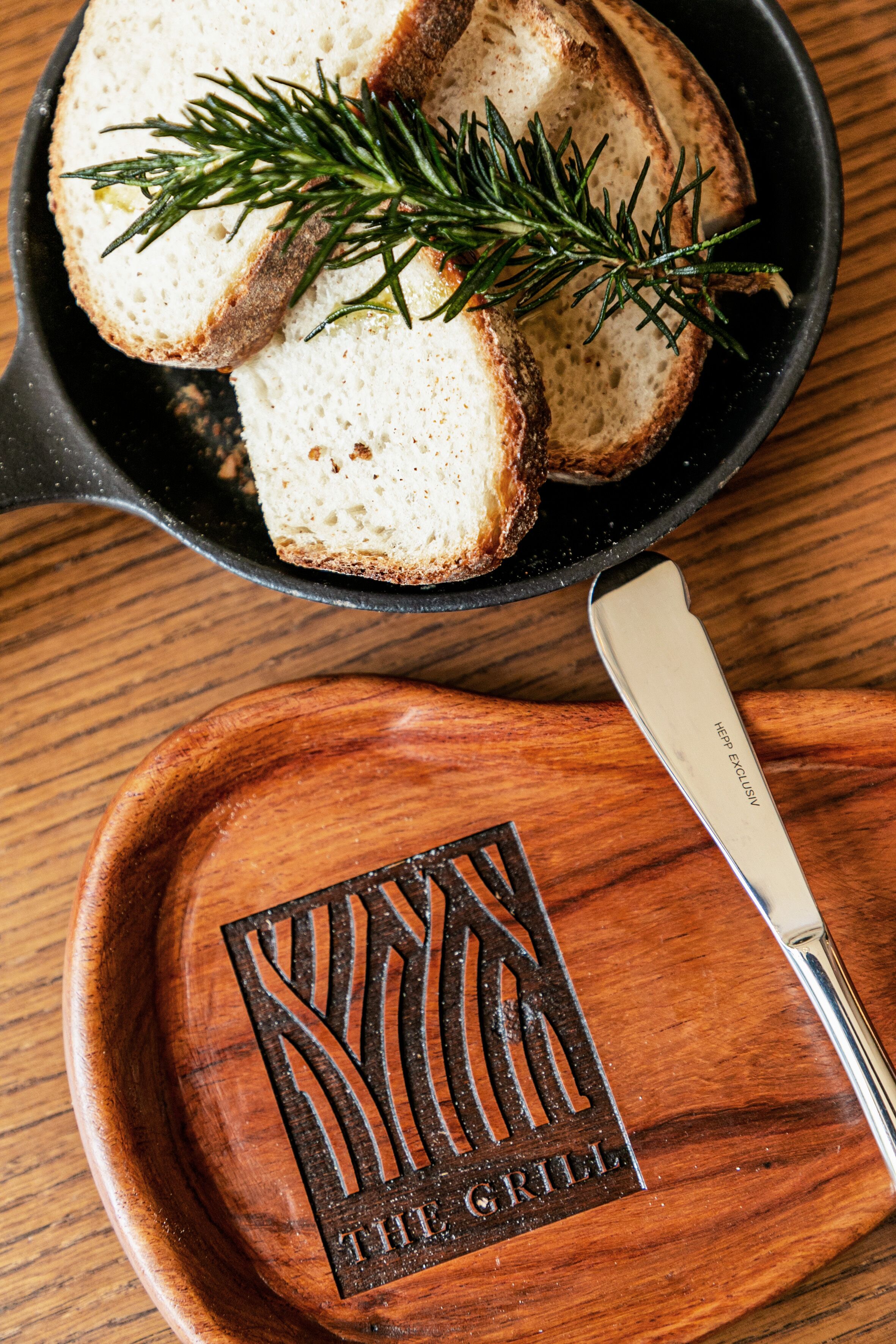 Una bandeja de madera con un cuchillo y una rebanada de pan de romero.
