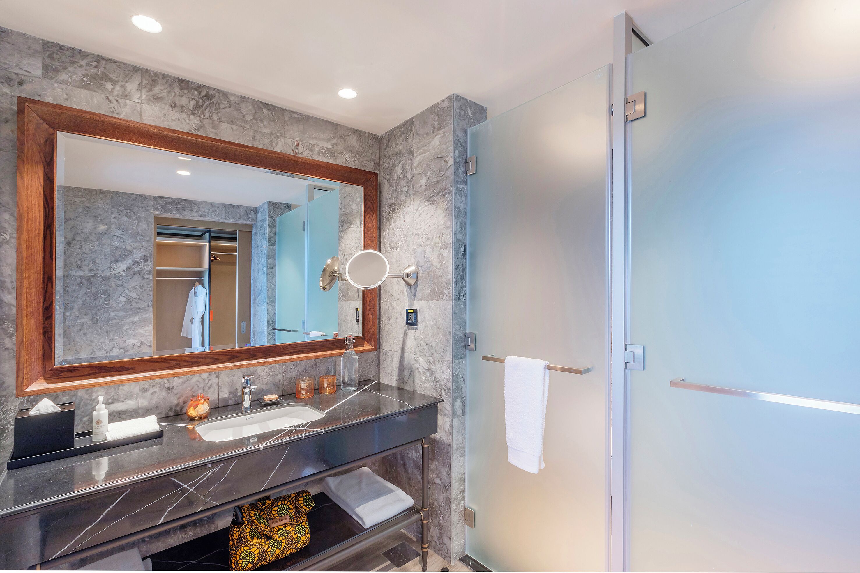 Une salle de bain moderne avec un meuble-lavabo en marbre, un grand miroir et une cabine de douche en verre.