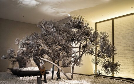 A room with a circular stone floor, a bonsai tree, and a traditional Japanese screen.