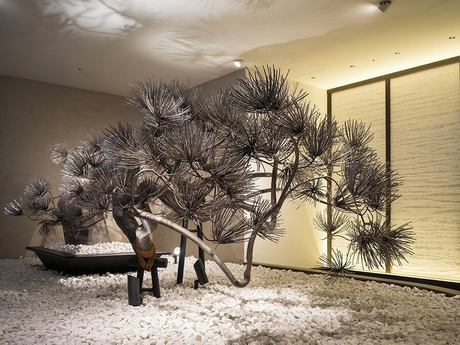 A room with a circular stone floor, a bonsai tree, and a traditional Japanese screen.