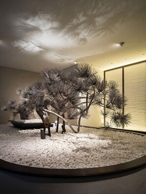 A room with a circular stone floor, a bonsai tree, and a traditional Japanese screen.