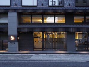 Un bâtiment moderne doté d’une façade en verre, d’une entrée bien visible et d’une enseigne indiquant « DHAWA TUSK STUDIO ».
