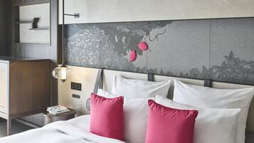 Habitació d'hotel amb llit, almoines, una tauleta de nit, làmpada i un mur amb un panell decoratiu.