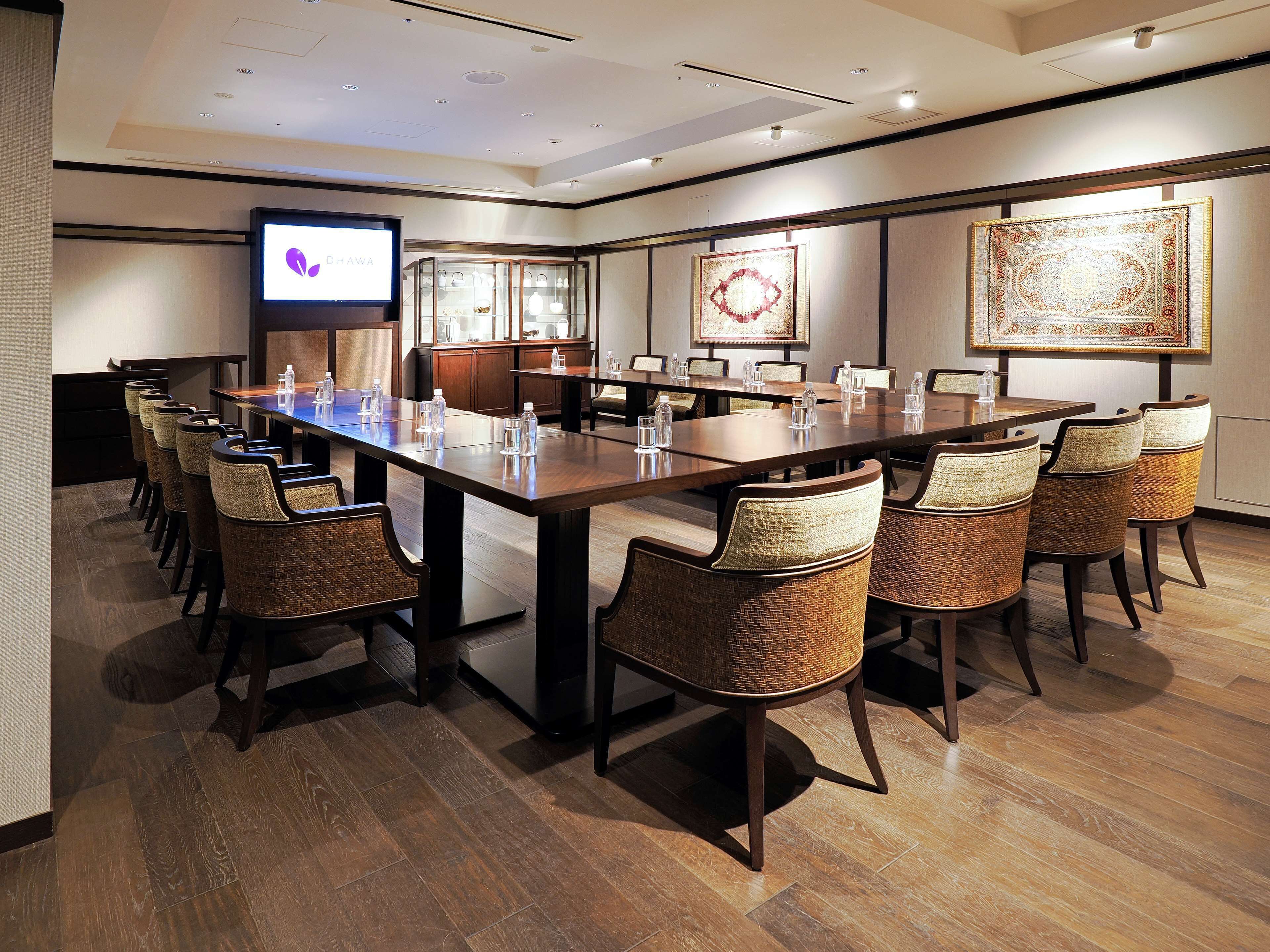 A conference room with a long table, chairs, a screen, and decorative wall art.
