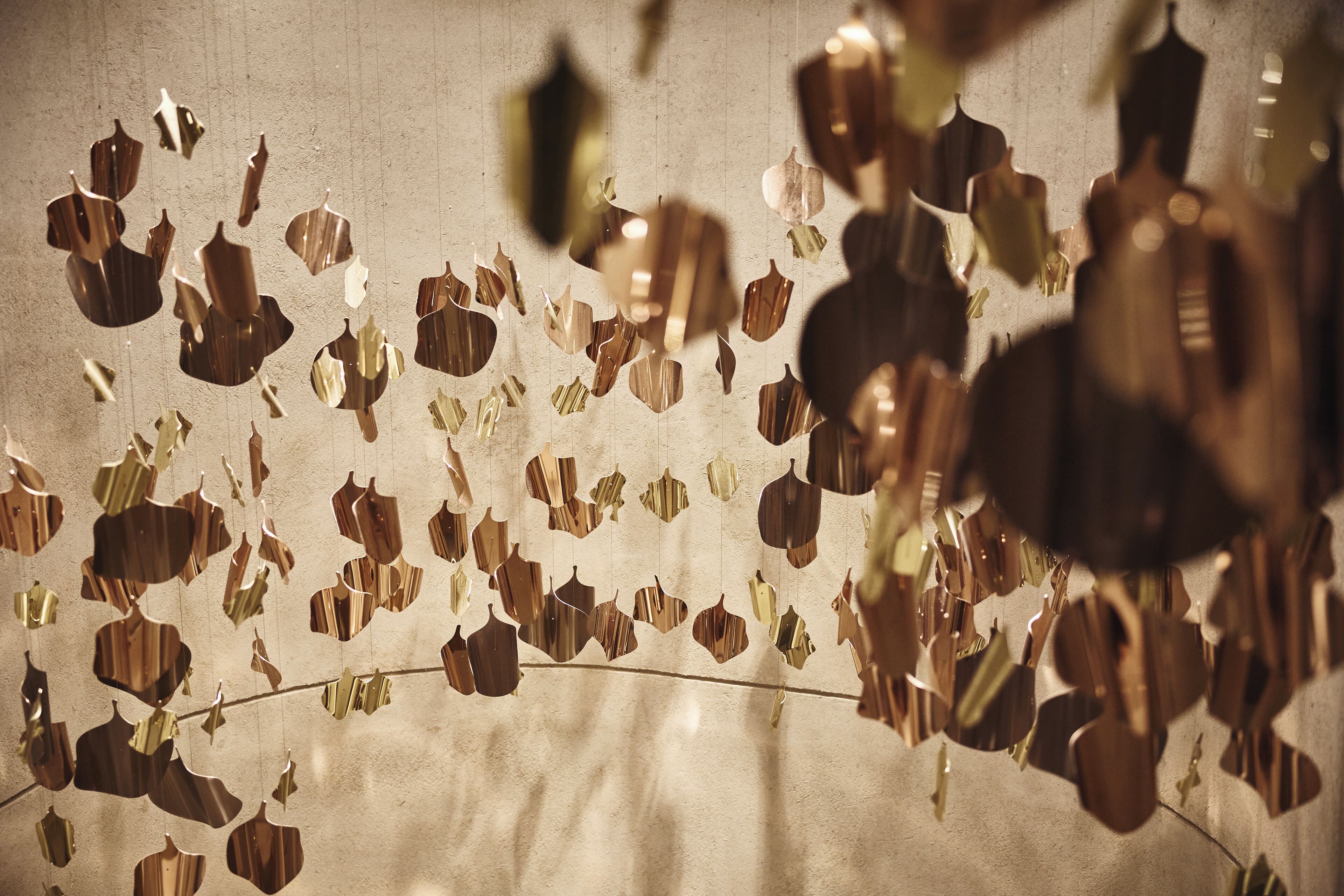 A wall with hanging metallic leaf decorations.
