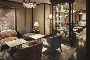 A well-lit living room with a sofa, armchairs, a coffee table, a lamp, and a glass display cabinet with decorative items. - Dhawa Yura Kyoto (Kyoto)