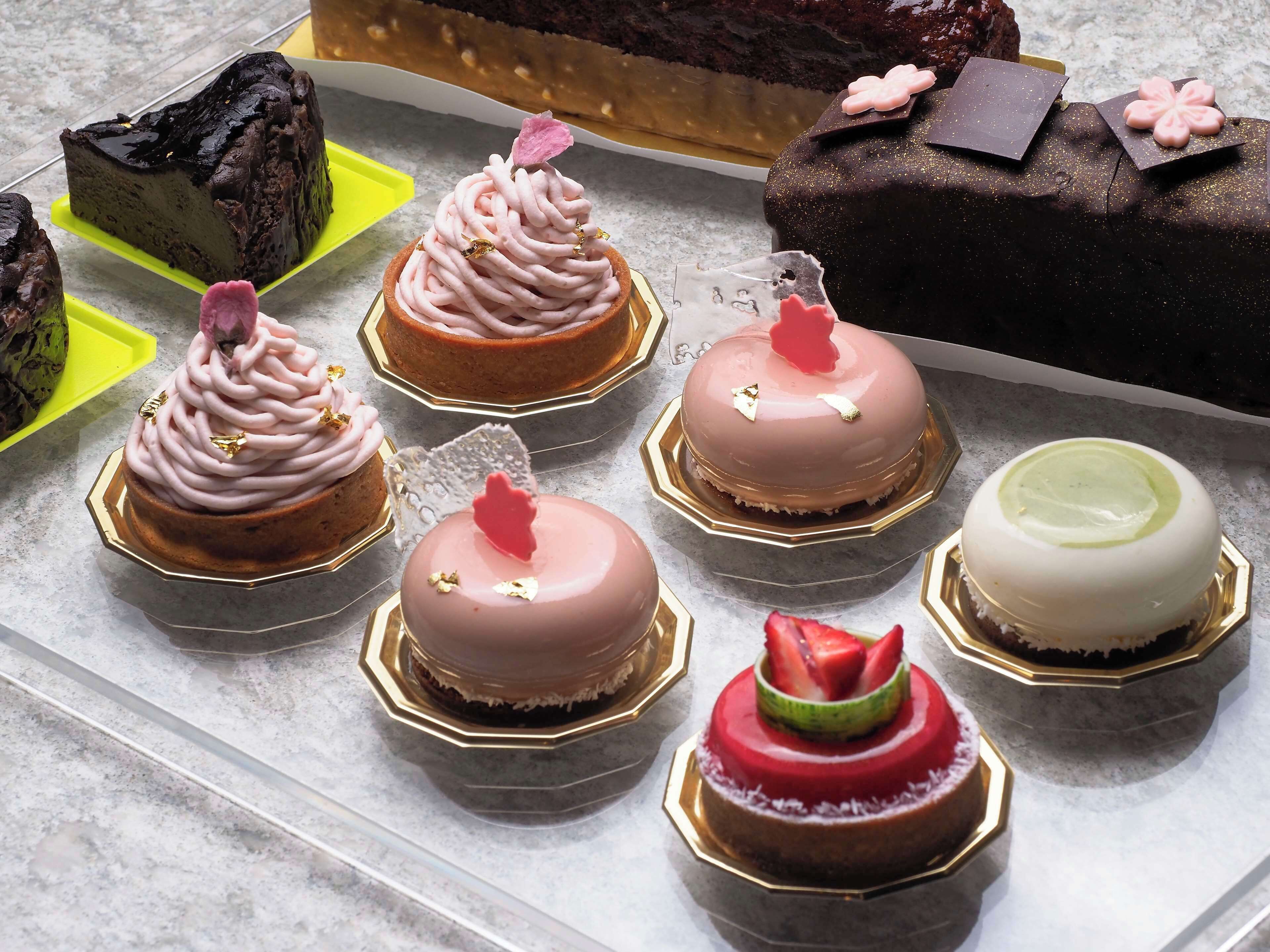 A variety of cakes on a table with different shapes and decorations.