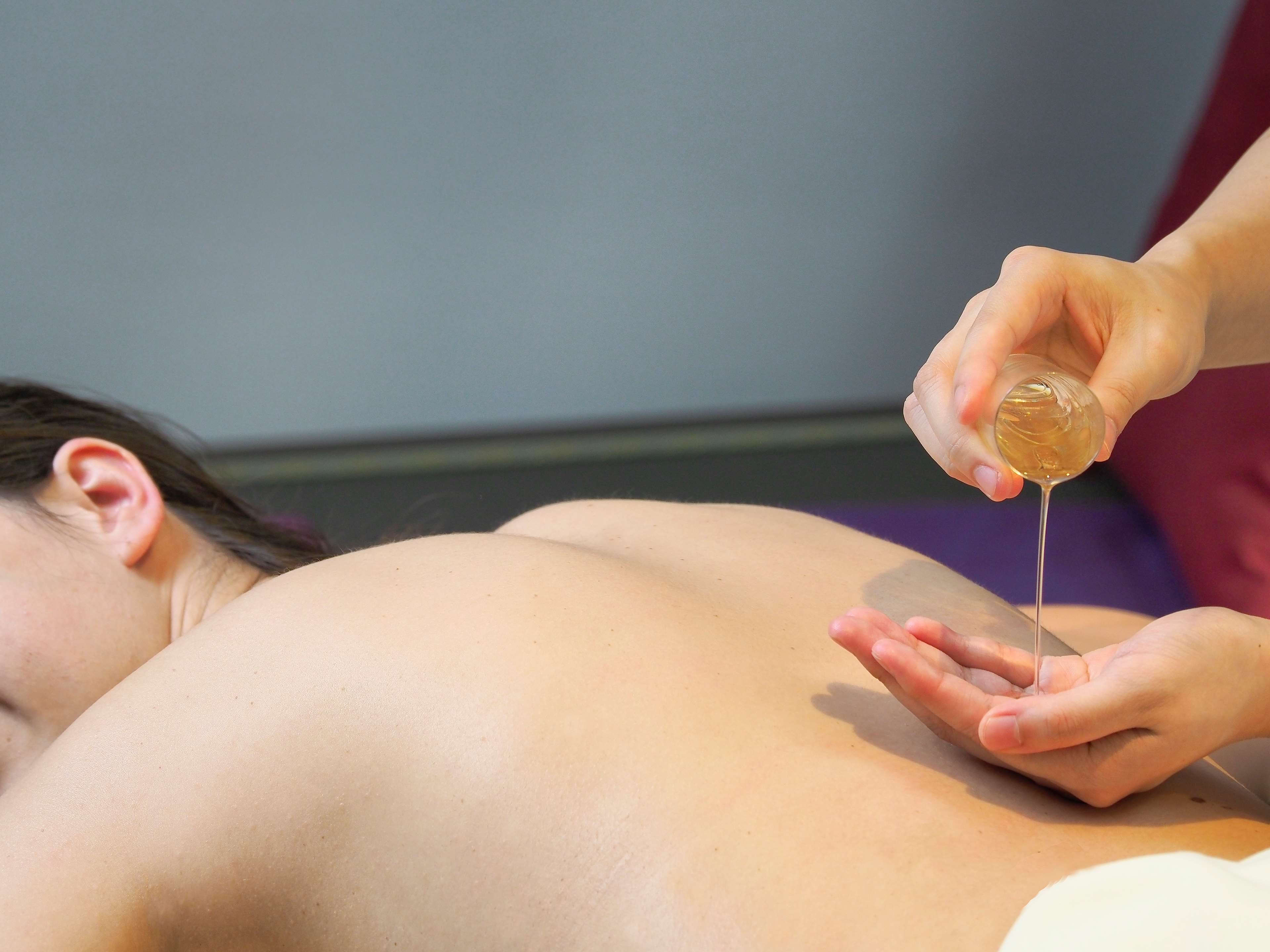 A person lying down with a hand applying a liquid substance to their back.