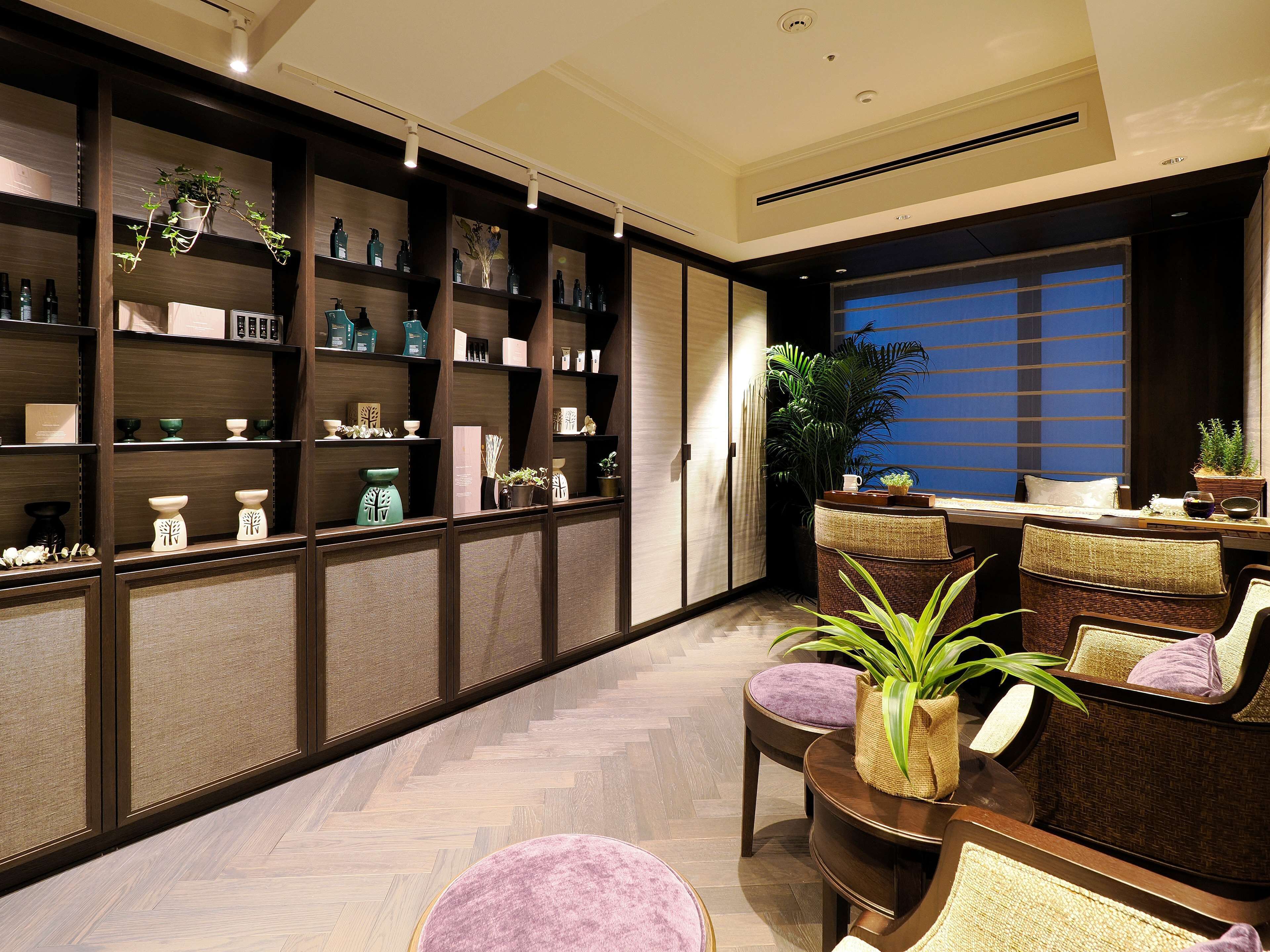 A modern interior with a herringbone floor, wooden shelving with various items, and a seating area with chairs and a round table.