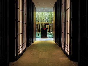 A corridor with a central pathway leading to a seating area, flanked by vertical paneling on both sides.