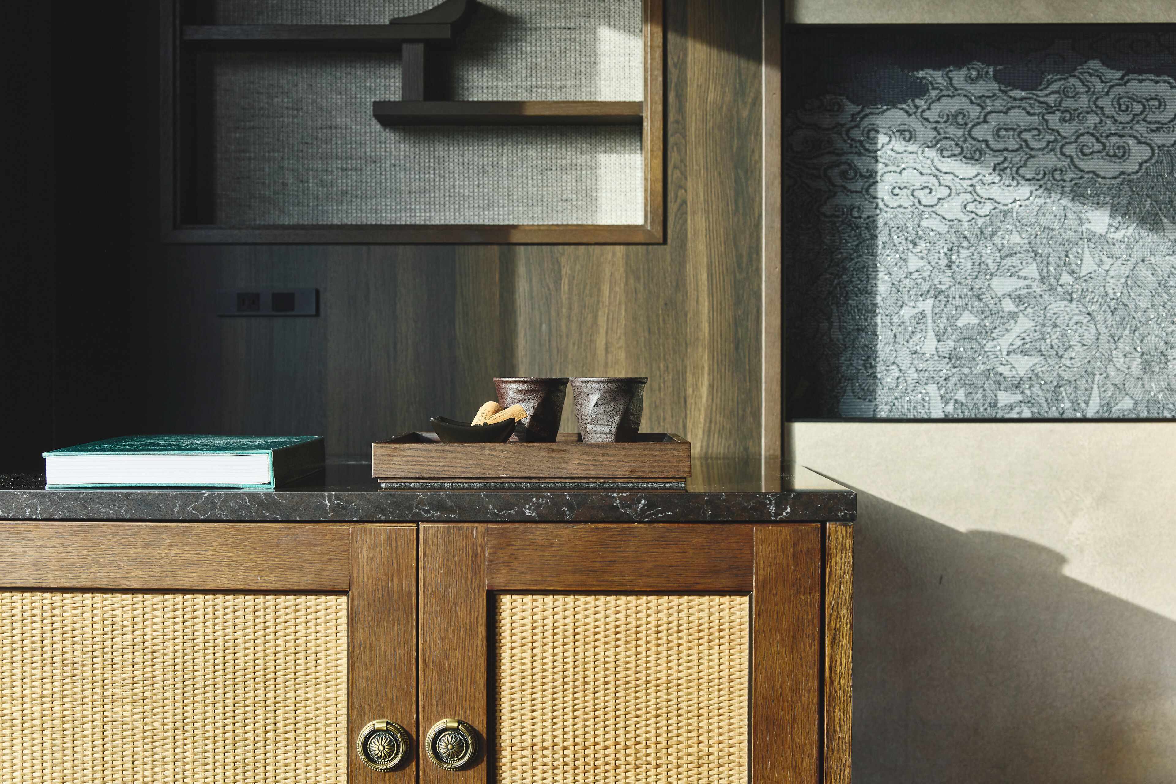 A wooden cabinet with a woven texture, a framed artwork, and a small book on top.