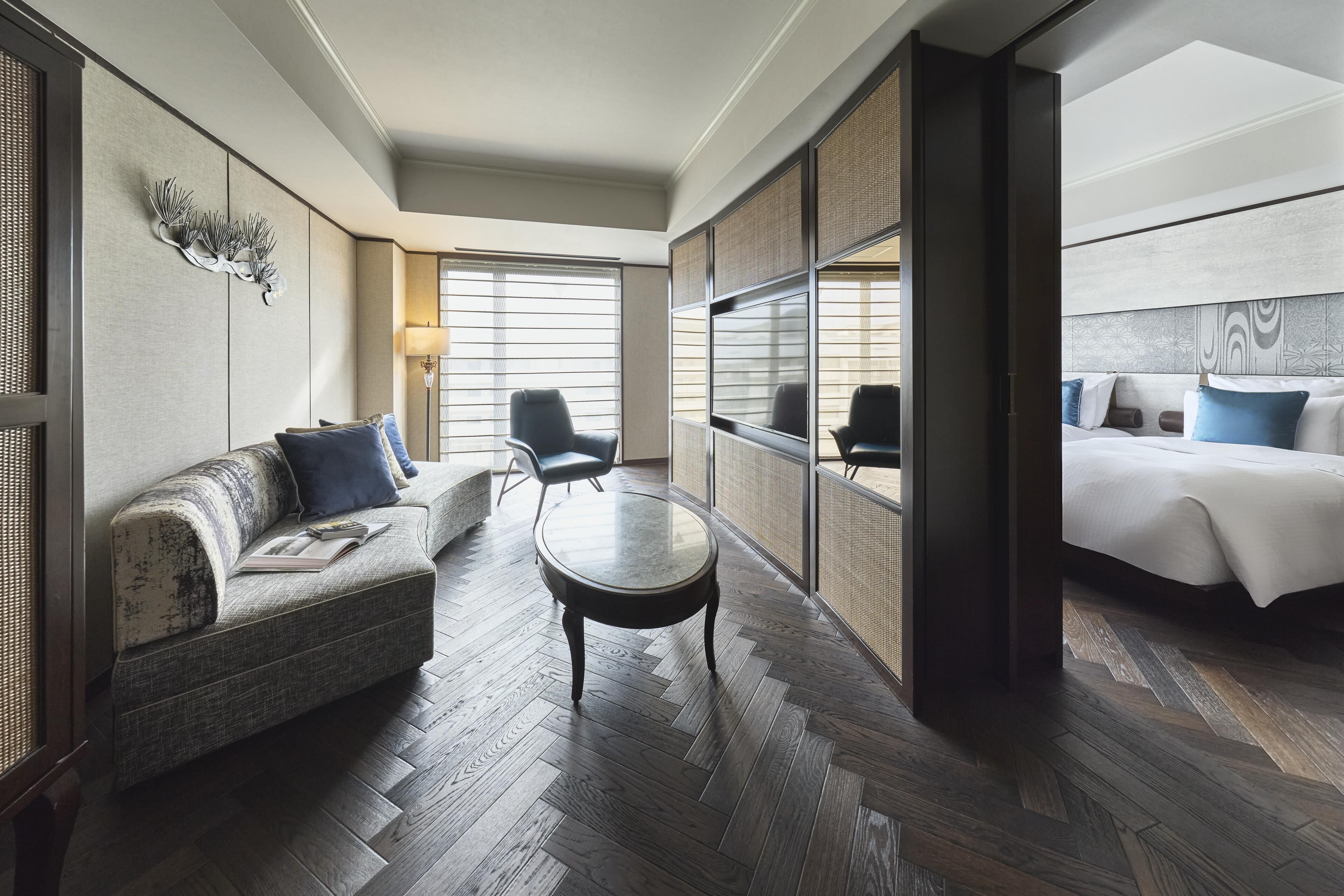 A hotel room with a sofa, a round table, a bed, and a large window.