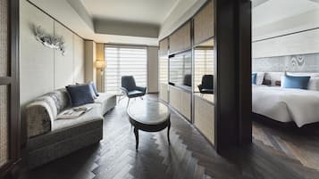 A hotel room with a sofa, a round table, a bed, and a large window.