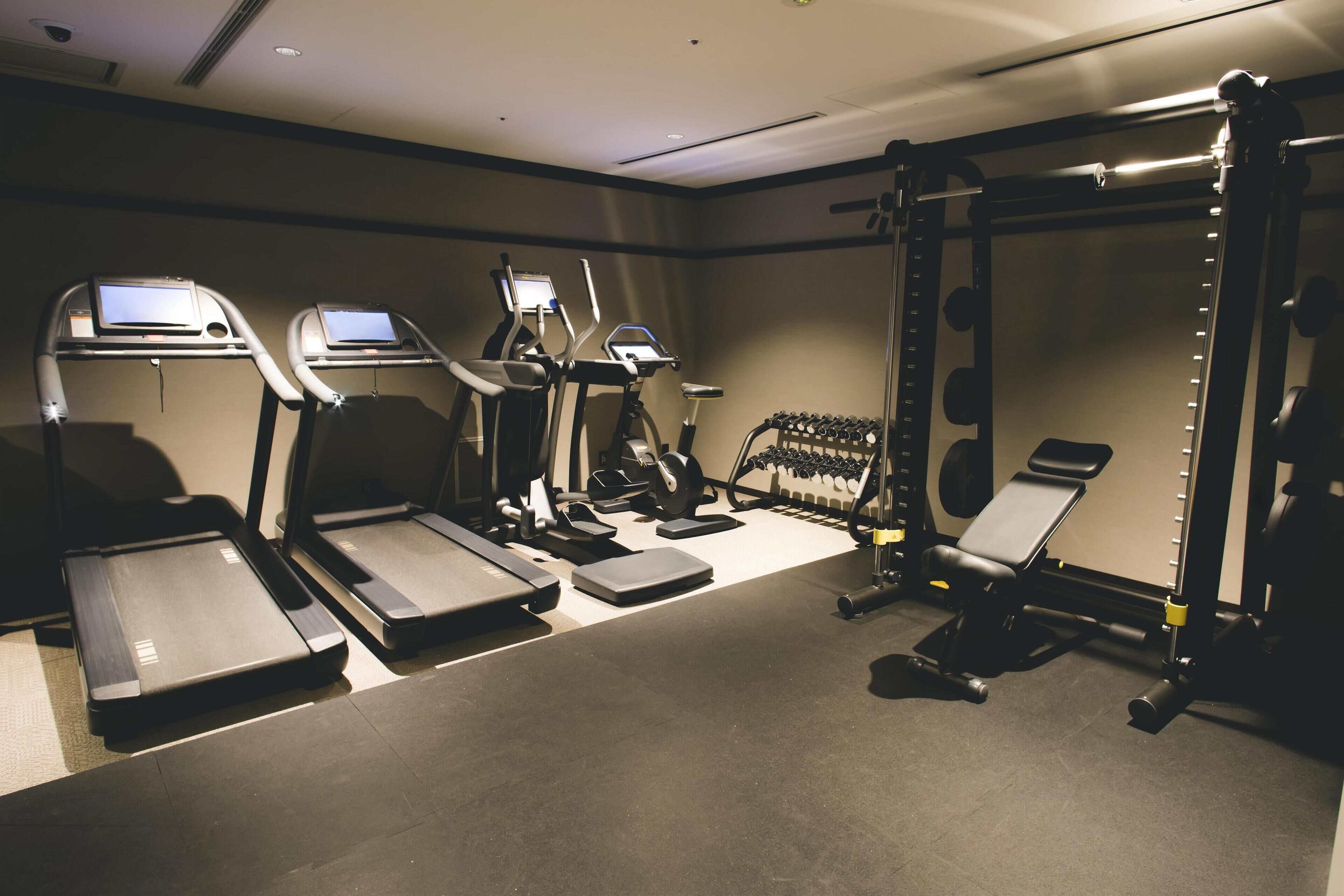 A gym with treadmills, elliptical machines, and weightlifting equipment.