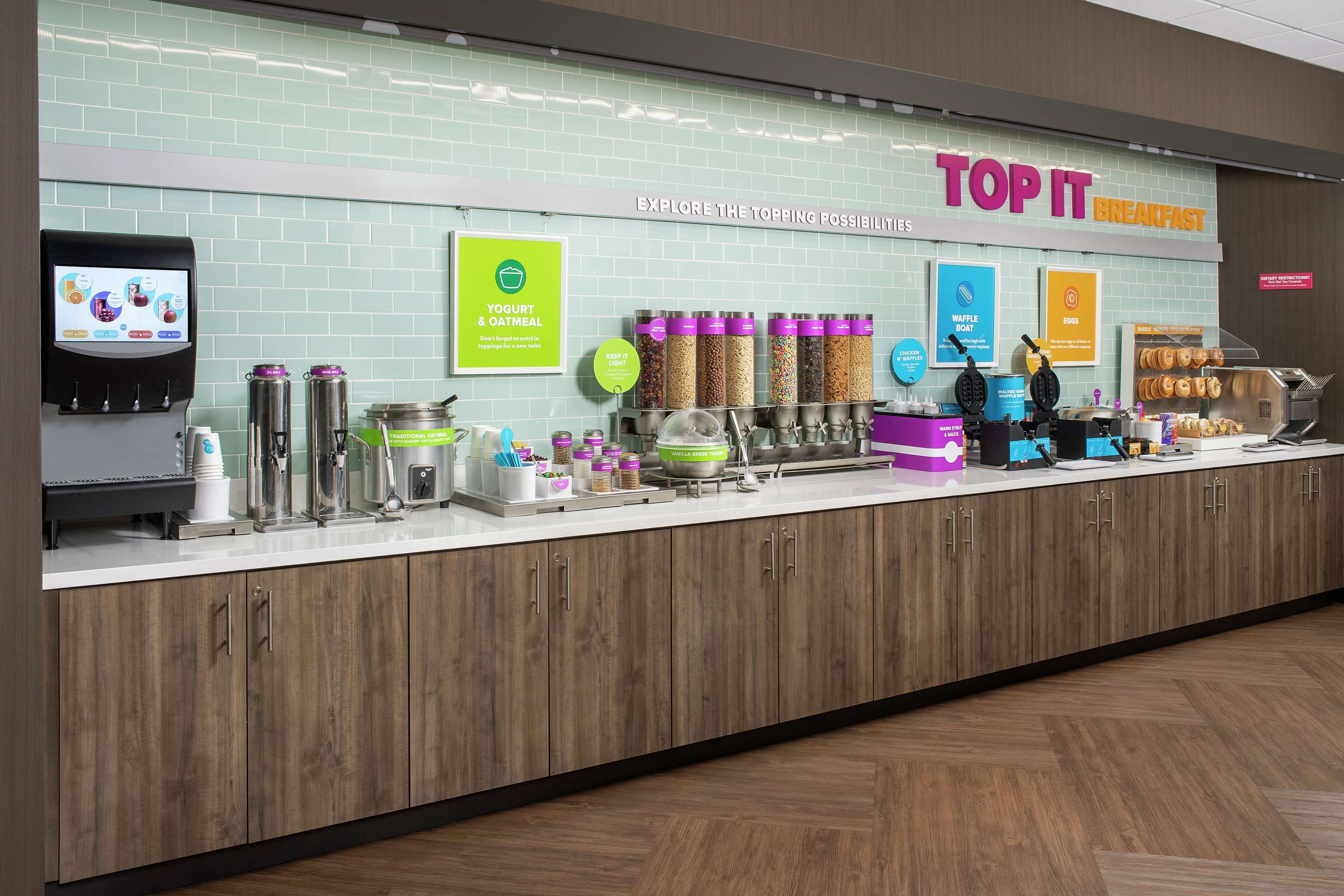 A breakfast counter with a variety of food options, including yogurt, waffles, and eggs.