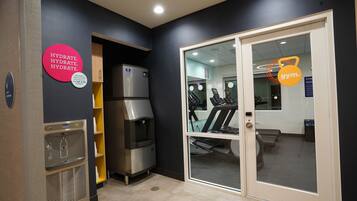 A gym area with a water dispenser, a treadmill, and a mirrored wall.