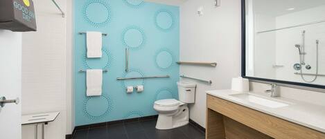 A modern bathroom with a white toilet, a sink with a mirror, and a blue wall with circular patterns.