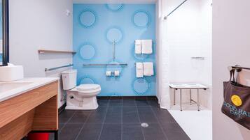A modern bathroom with a blue wall, white fixtures, and a red bucket.
