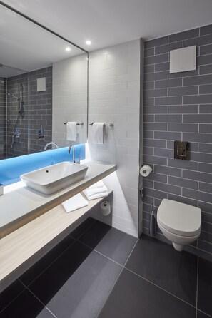 A modern bathroom with a large mirror, a white sink, a blue bathtub, and a toilet. - Holiday Inn Express Merzig by IHG (Merzig)