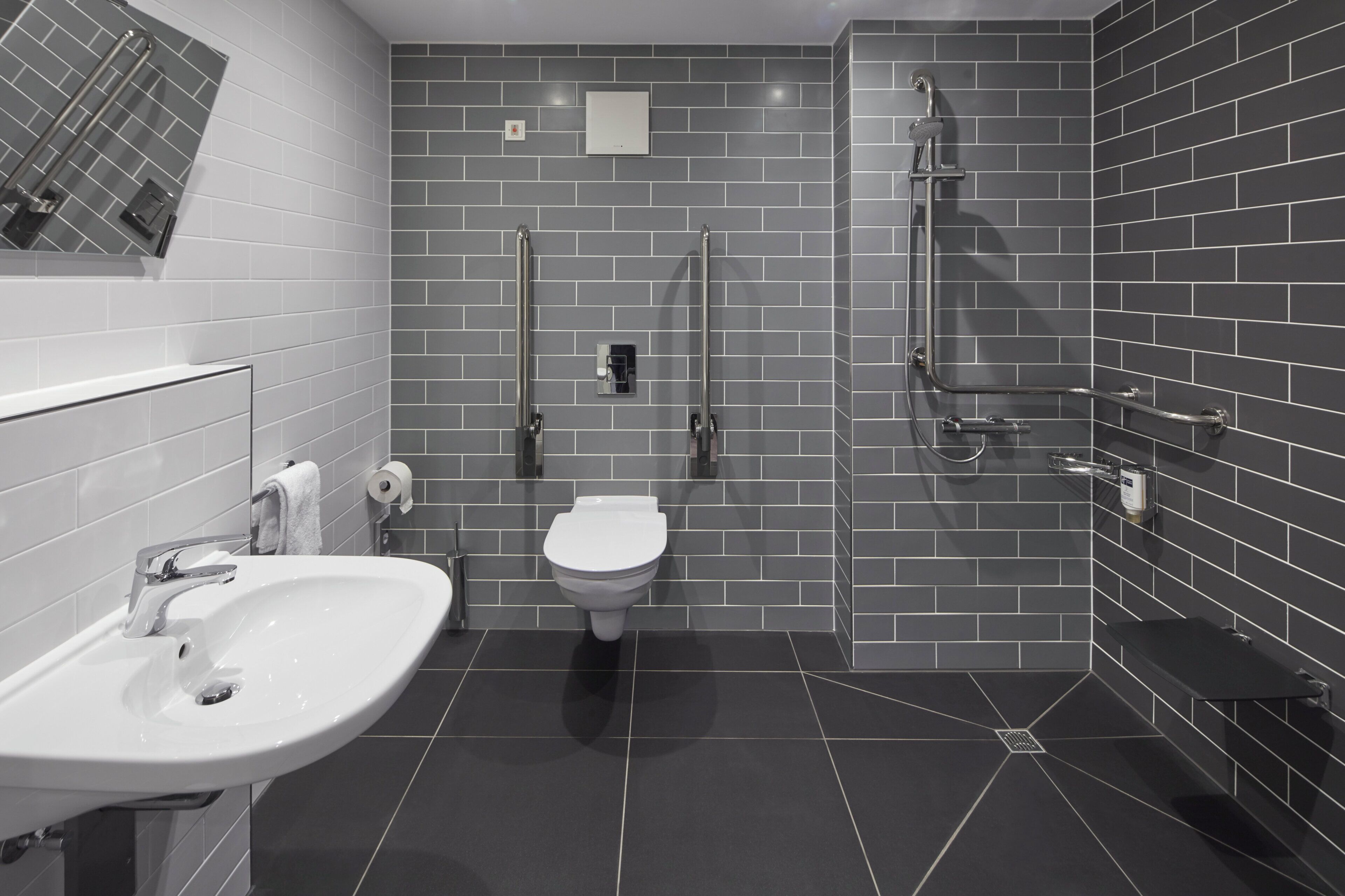 A modern bathroom with a white sink, toilet, and shower area.