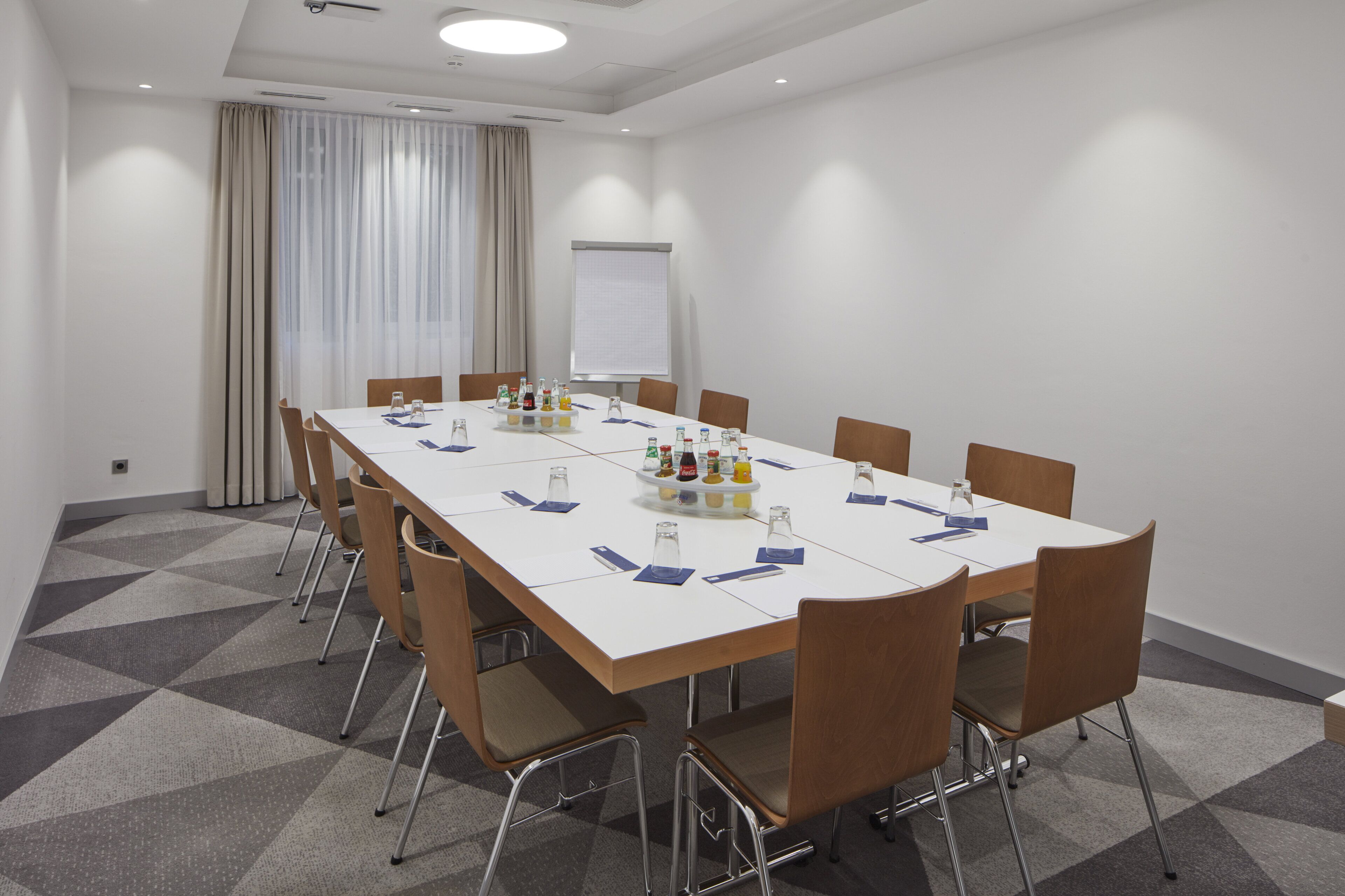 A conference room with a long table, chairs, and a projector screen.