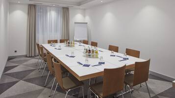 A conference room with a long table, chairs, and a projector screen.