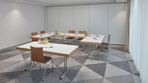 Un salón de conferencias con una larga mesa, sillas y piso alfombrado.