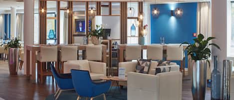 A modern hotel lobby with seating areas, a reception desk, and decorative lighting.