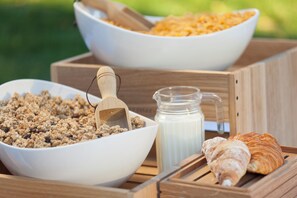 Two white bowls containing granola and cereal, a wooden scoop, a milk jug, and a croissant on a wooden tray. - Holiday Inn Express Merzig by IHG (Merzig)