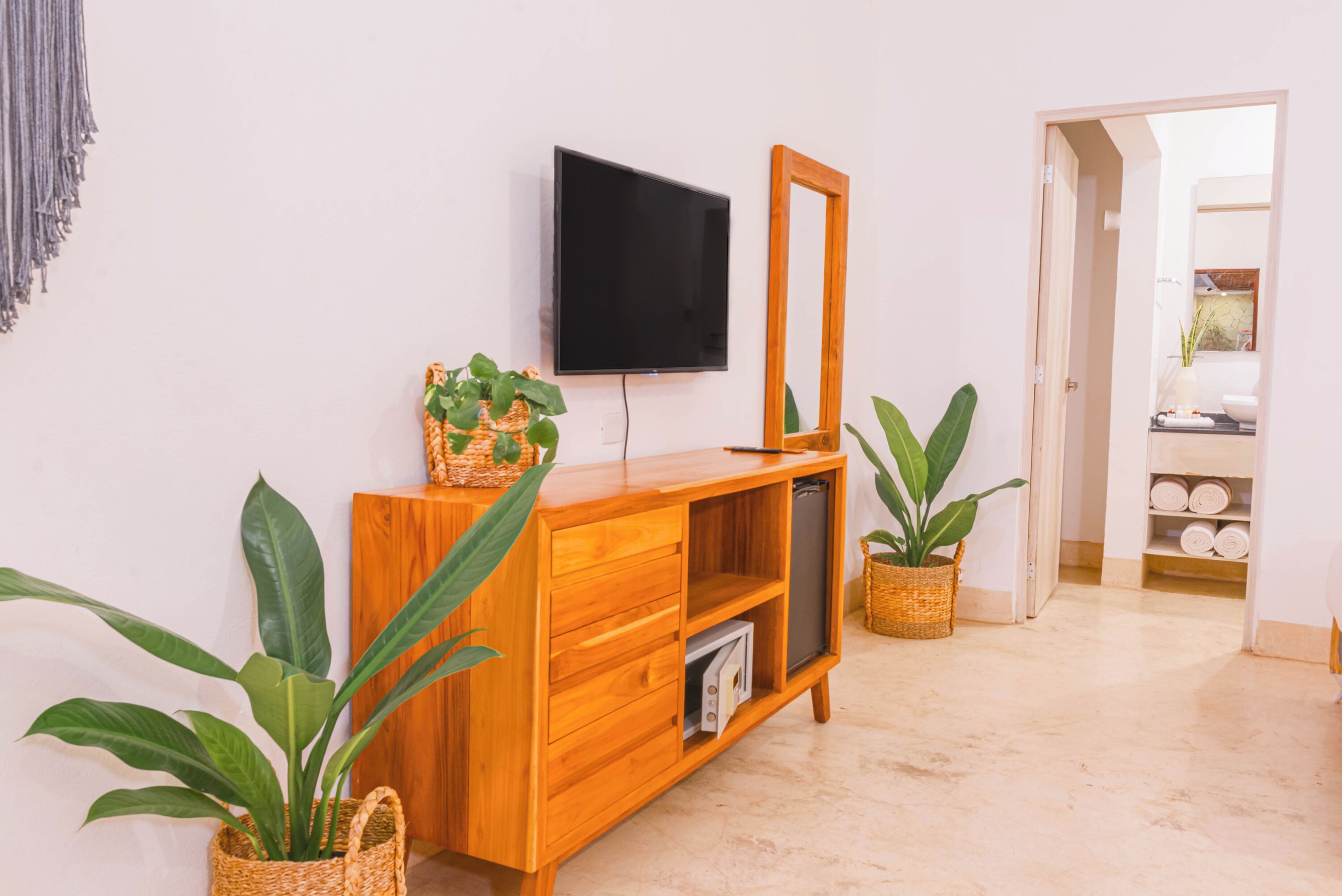 Een houten console tafel met een flatscreen televisie, een spiegel en potplanten.