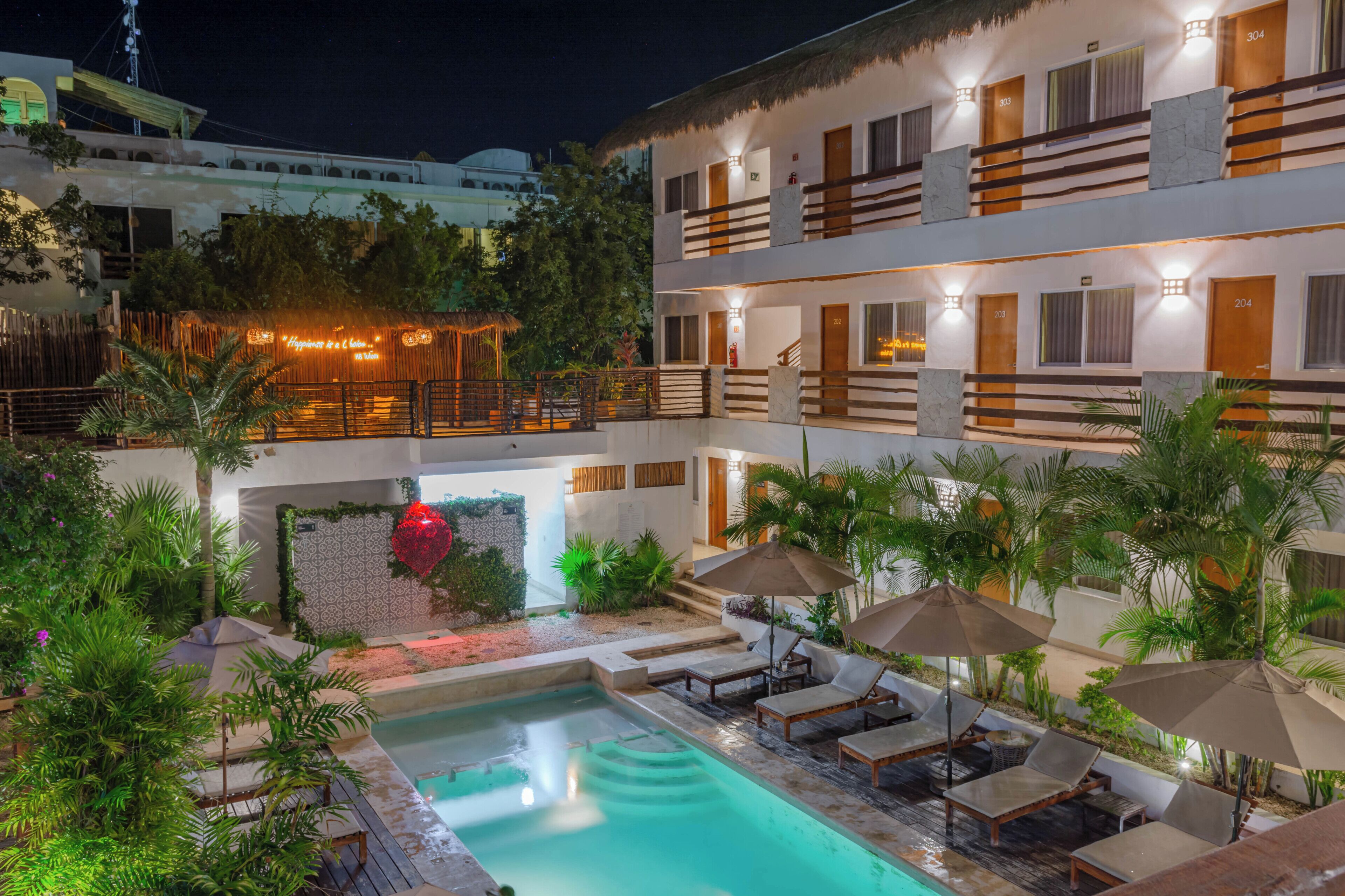 A hotel with a pool area, outdoor seating, and a well-lit facade.