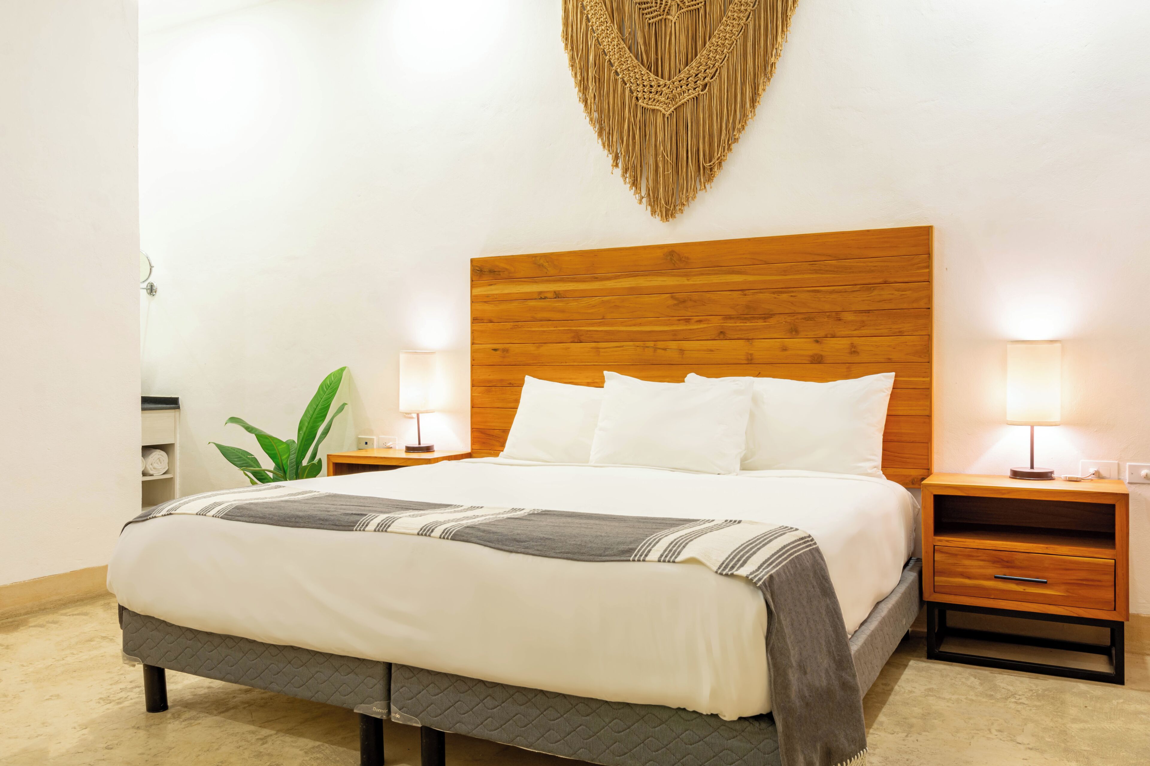 A neatly made bed with a wooden headboard, two bedside tables with lamps, and a wall-mounted decorative piece.