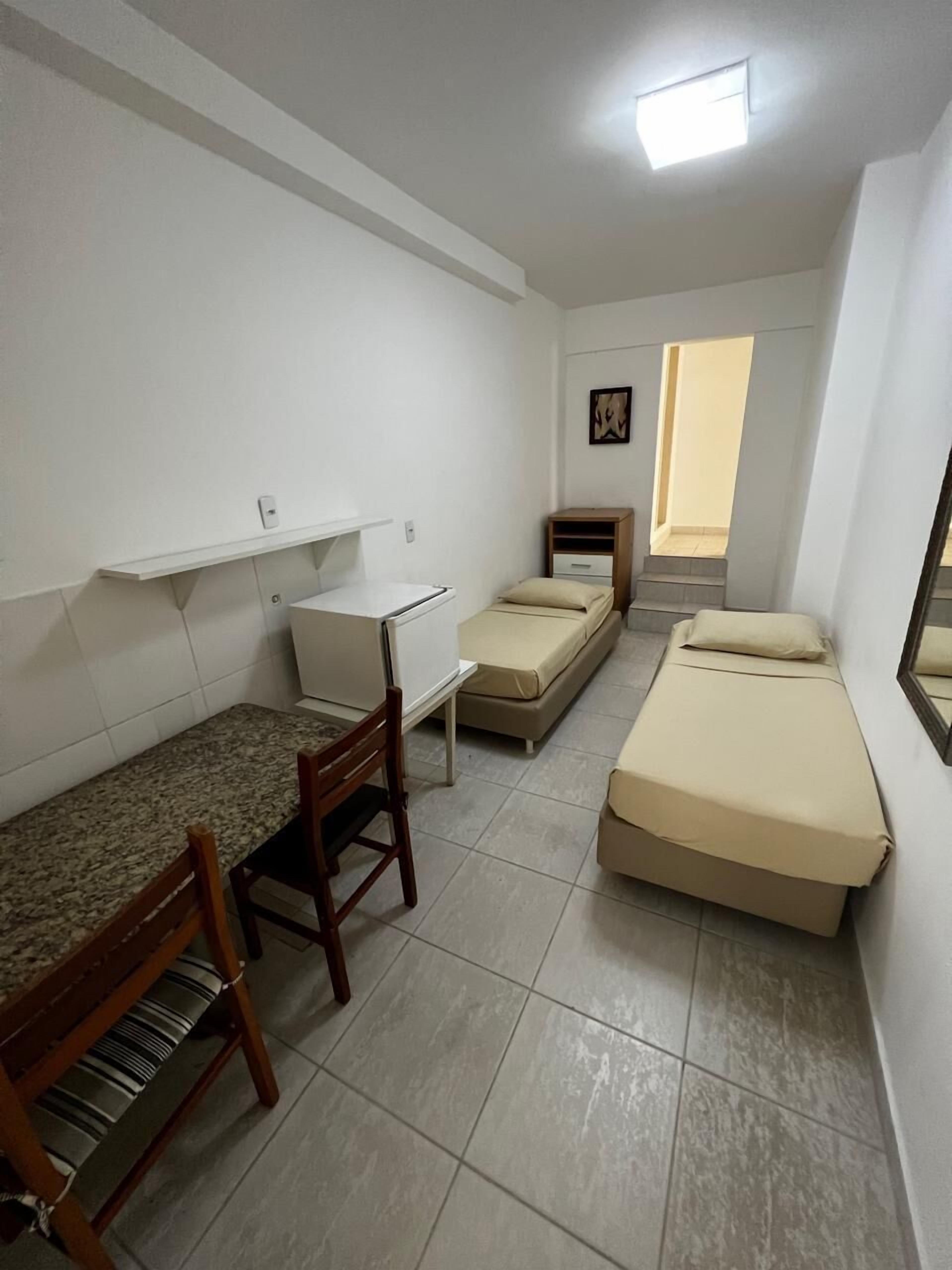 A small, clean room with a bed, a desk, and a chair.