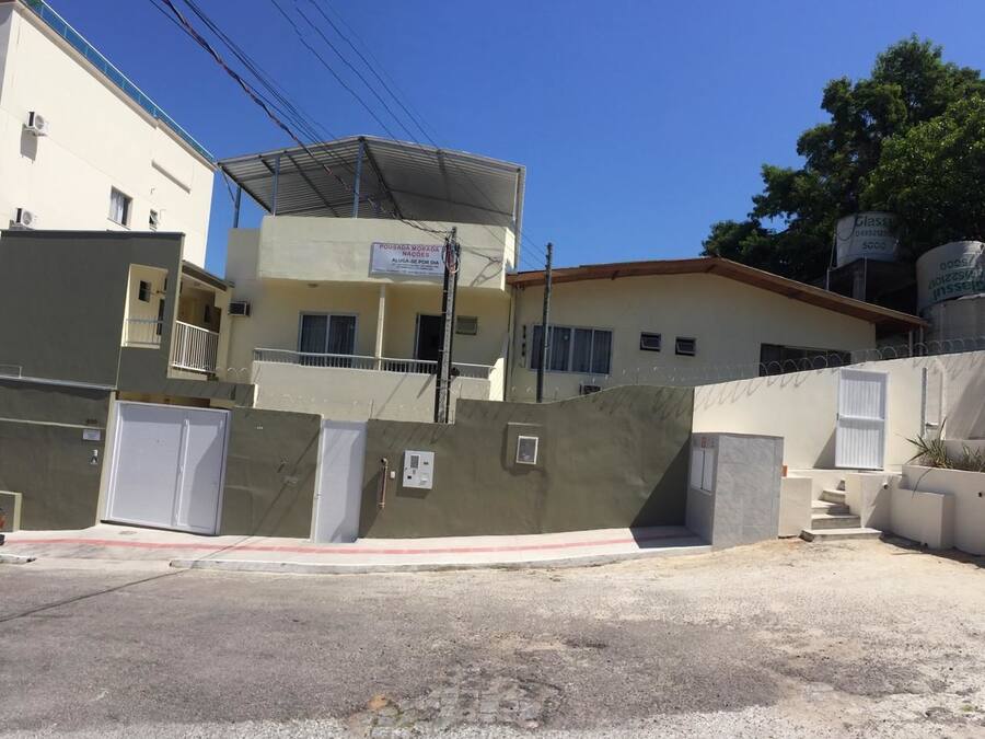 A multi-story building with a flat roof, a gated entrance, and a visible signboard.