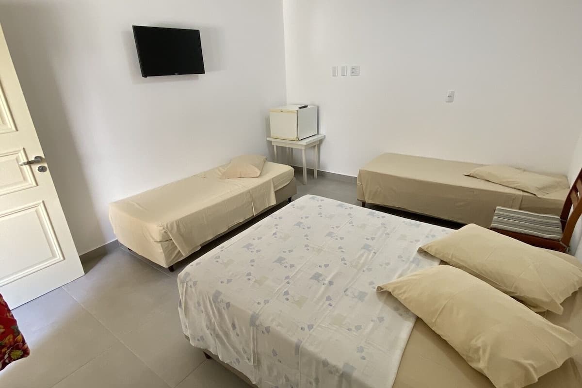 Una habitación con una cama, dos mesitas de noche, un televisor montado en la pared y una puerta.