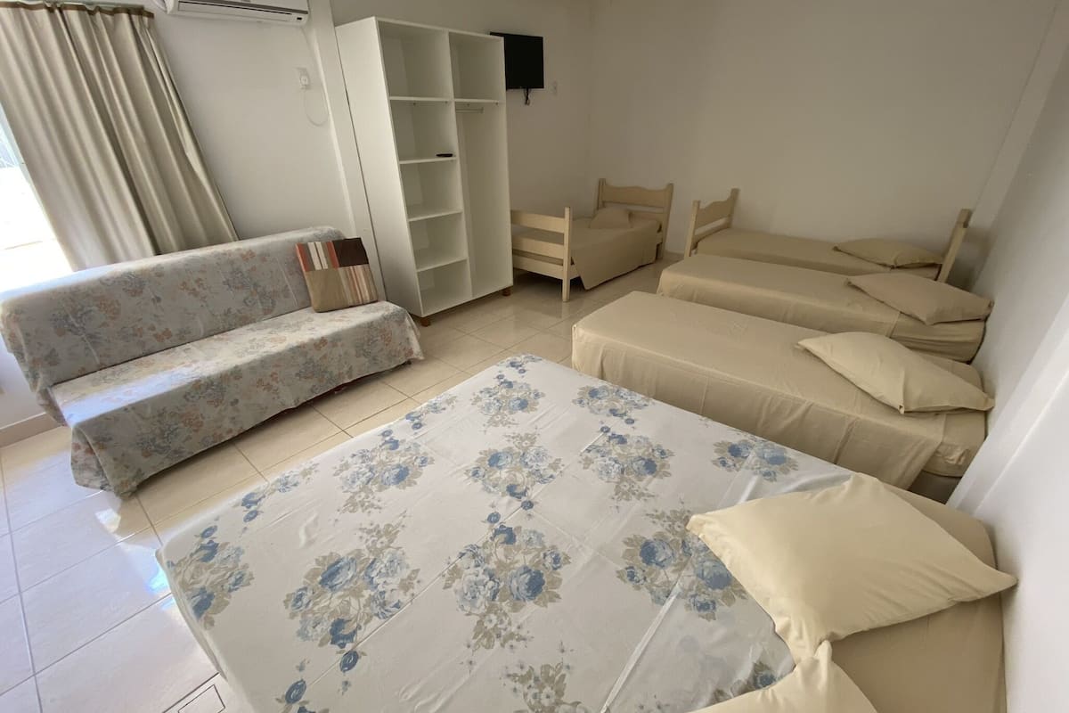 Un dormitorio con cama, sofá, armario y televisor.