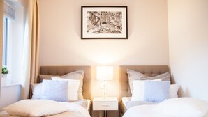 Une chambre d’hôtel avec deux lits, une table de chevet avec une lampe et un tableau encadré au mur.