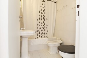 Een badkamer met toilet, hygiëneschuimer en wastafel.