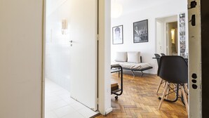 Un intérieur moderne avec un parquet en chevrons, une chaise noire, un canapé et un coin repas.