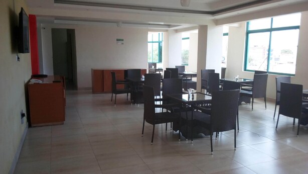 A spacious dining area with multiple tables and chairs, large windows, and a reception desk. - Daiichi Hotels (Isiolo)