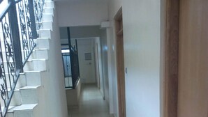 A narrow, tiled hallway with a staircase on the left and a wooden door on the right. - Daiichi Hotels (Isiolo)