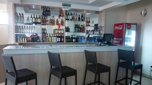 A bar area with a counter, multiple liquor bottles, and a Coca-Cola refrigerator. - Daiichi Hotels (Isiolo)