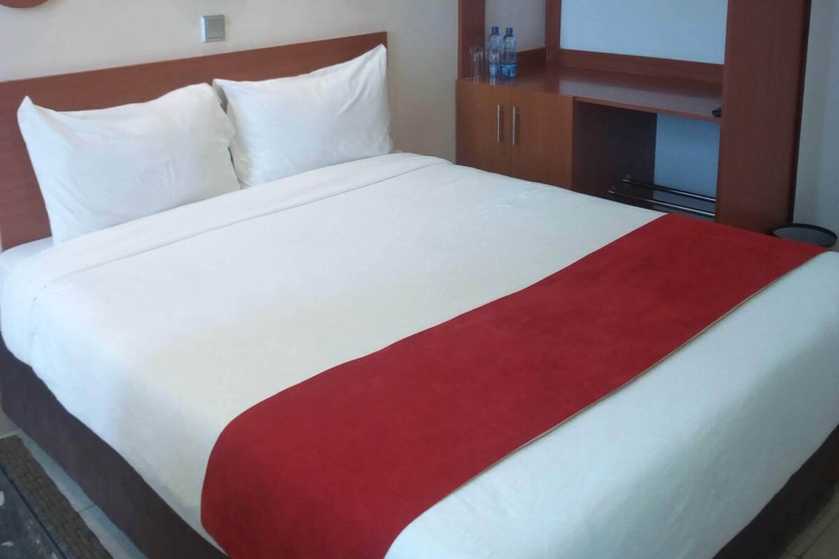 A hotel room with a large bed, a wardrobe, and a mirror.