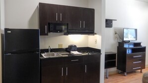 A compact kitchen with dark cabinets, a microwave, a toaster, and a small TV. - Studio 6 - Colorado Springs - Air Force Academy  (Colorado Springs)