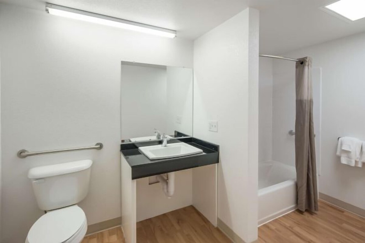 A bathroom with a toilet, sink, mirror, and shower.