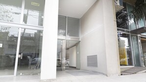Una entrada de edificio moderna con puertas de cristal grandes, una escalera de metal y un sistema de ventilación.