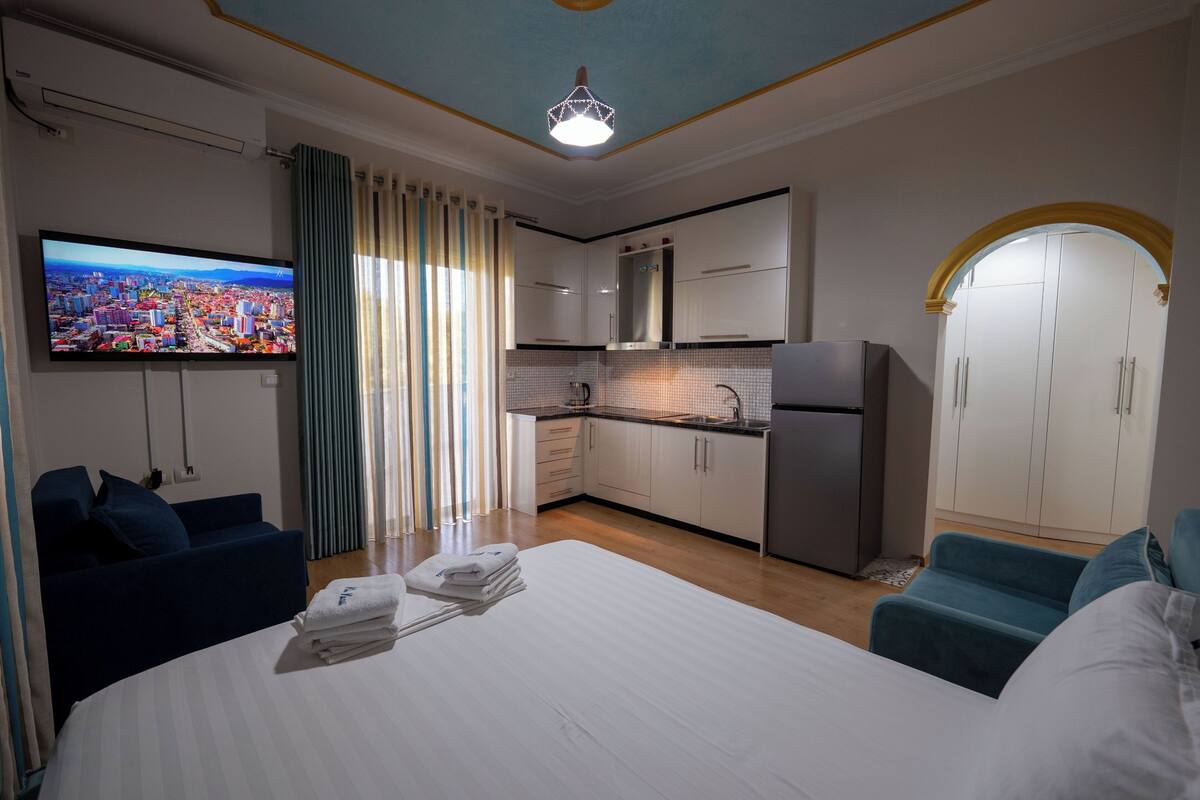 Una habitación de hotel con cama, televisión, kitchenette y armario.