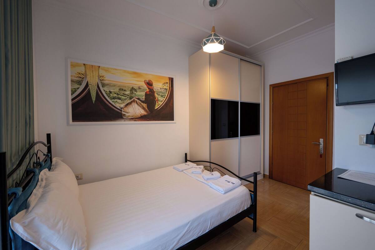 Un dormitorio con cama, un cuadro, un armario, un escritorio y un televisor.
