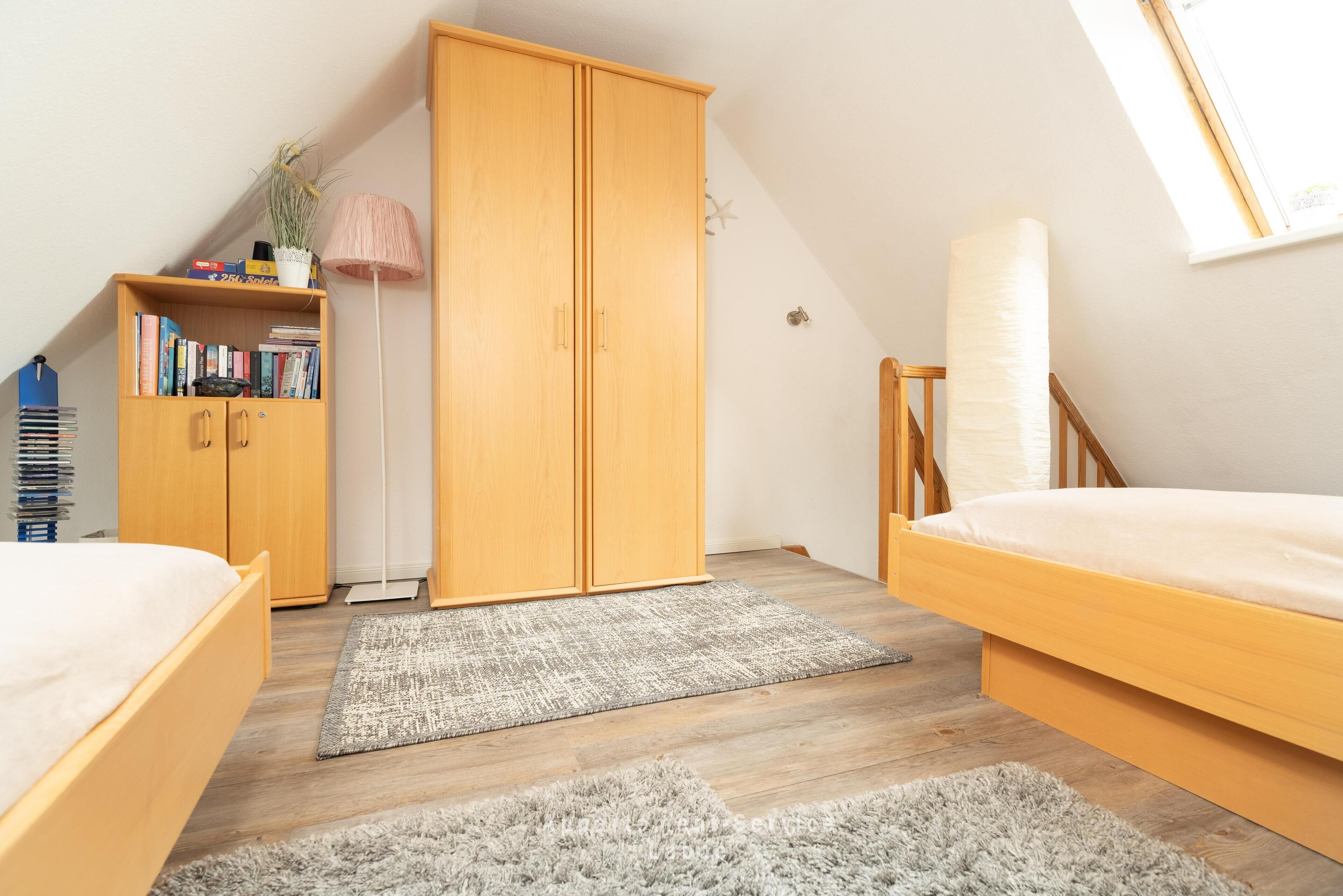 A bedroom with a loft bed, a wardrobe, a bookshelf, and a skylight.